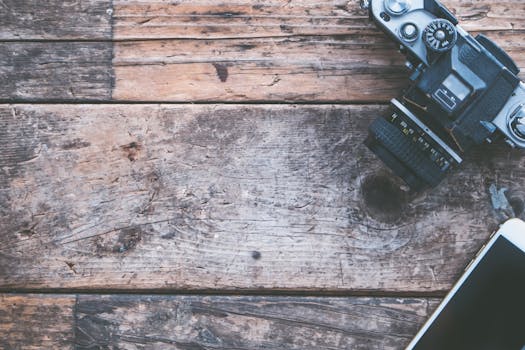 将老式相机和智能手机平放在质朴的木板上，非常适合创意项目