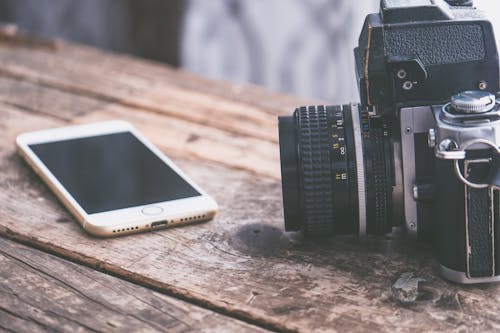 Iphone Dourado Perto Da Câmera Dslr Na Mesa