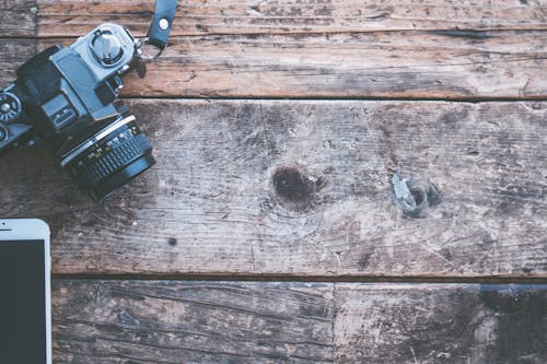 Black and Gray Dslr Camera on Brown Wooden Plank