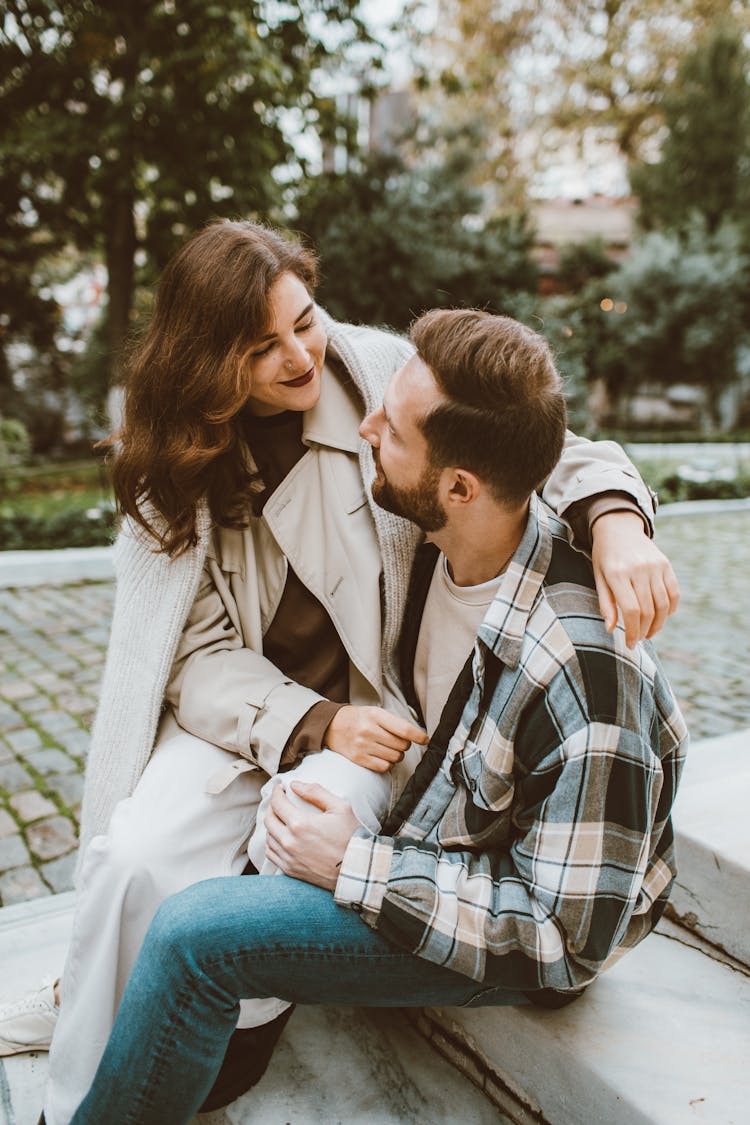 A Smiling Woman Sitting On The Man's Lap