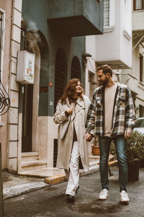Free A couple enjoys a leisurely stroll holding hands on a cozy city street during fall. Stock Photo