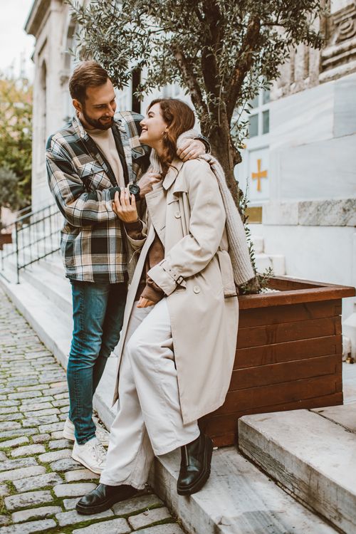 Free A happy couple enjoying a tender moment on a picturesque street, wrapped in cozy coats. Stock Photo
