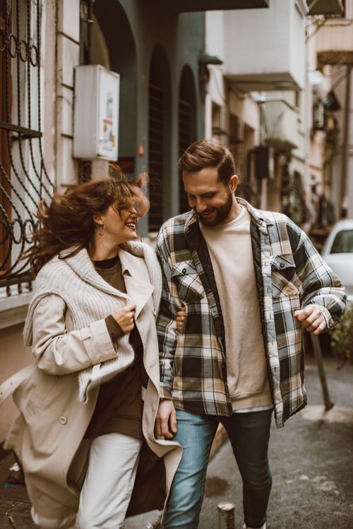 Free A joyful couple enjoys a walk down a charming city street, exuding happiness and connection. Stock Photo