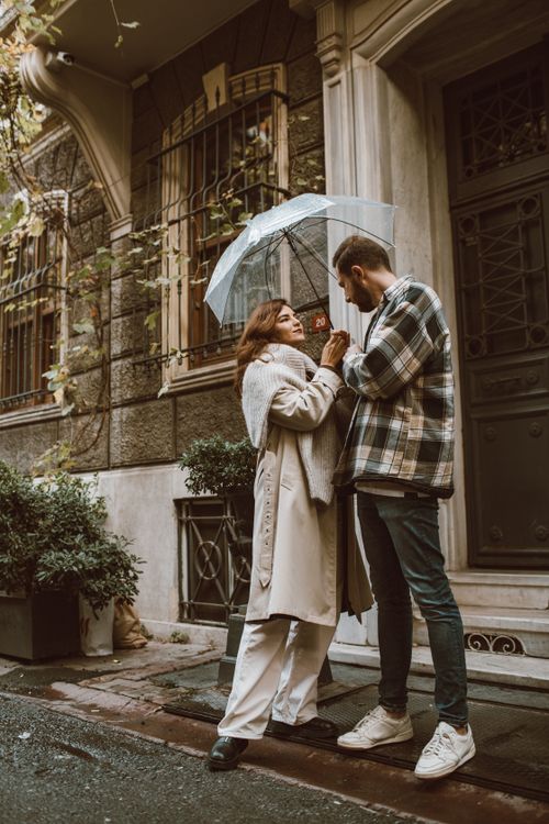 Free A romantic moment between a couple under an umbrella on a rainy city street. Stock Photo