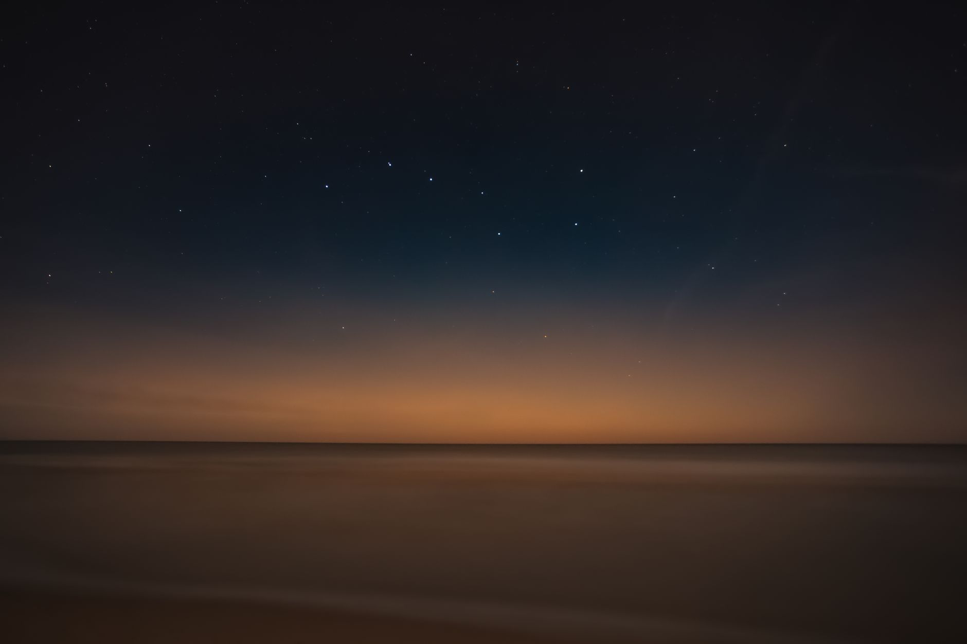 A serene night view of the calm sea and starry sky at Leba Beach, Poland.