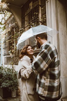 A couple enjoys a rainy autumn day under an umbrella, capturing a cozy and romantic moment outdoors.