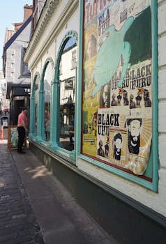 Street scene featuring a storefront with vintage posters and reflection in windows.