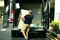 A Man Delivering a Cabinet From the Van
