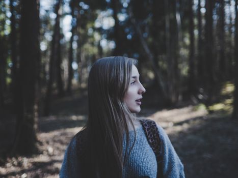 A woman gazes ahead as she stands in a serene forest setting, showcasing natural beauty.