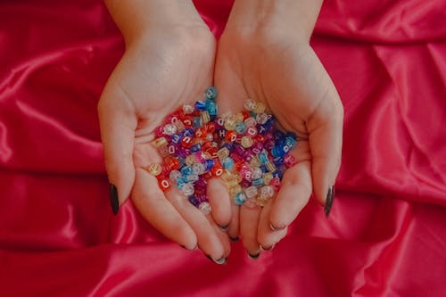 Free Person Holding Silver and Orange Beads Stock Photo