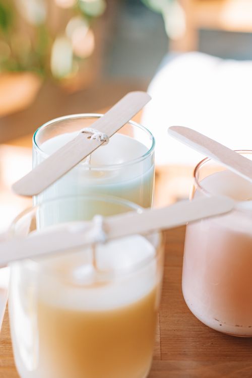 Free Close-up of handmade scented candles in glass jars with wooden wicks, sunlight streaming in. Stock Photo