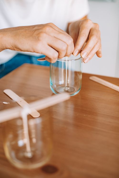 Free Hands working on a glass candle crafting project with wooden sticks. Stock Photo