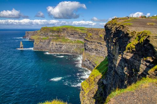 Free Experience the breathtaking views of the Cliffs of Moher against a vibrant blue sky in Ireland. Stock Photo