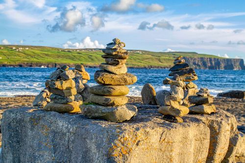 Free Balanced stone stacks on the scenic coast of Doolin, Ireland, with ocean and cliffs in the background. Stock Photo