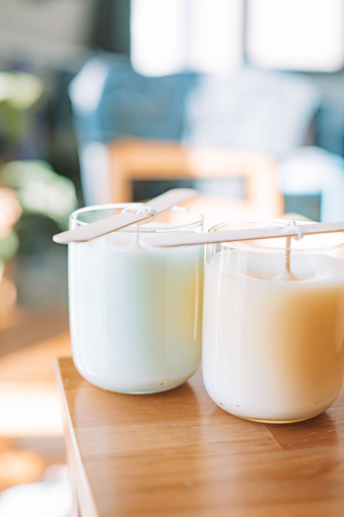 Two homemade candles setting with popsicle stick wick supports