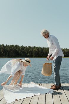 一对老年夫妇在阳光明媚的湖滨码头上准备野餐