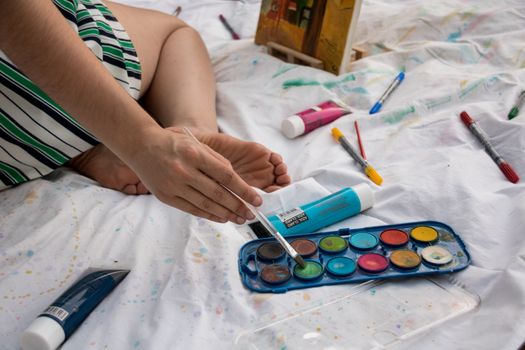 An artist's hand blends vibrant watercolors during a relaxing indoor painting session.