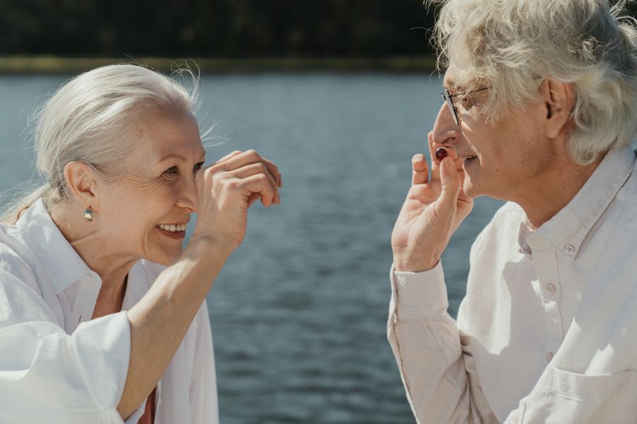 Older couple laughing together beside a lake, the kind of easy moment people hope free senior dating sites Canada can lead to