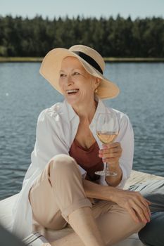 高级女士在码头边享受一杯葡萄酒，度过了一个夏天