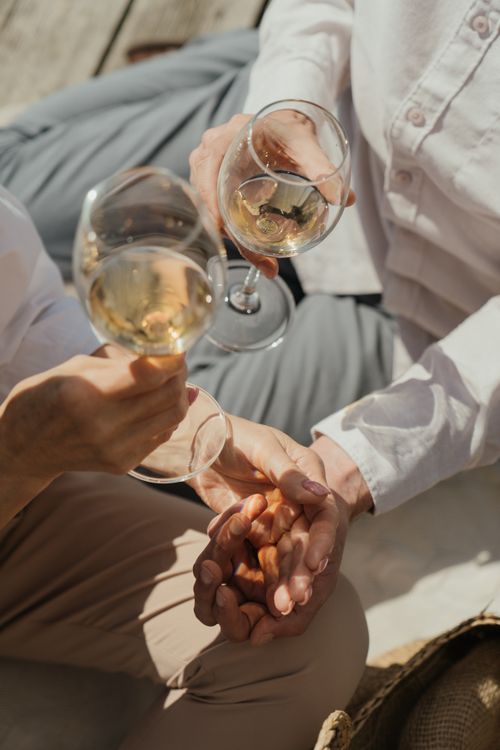 Free A romantic moment of a couple toasting with white wine outdoors. Stock Photo
