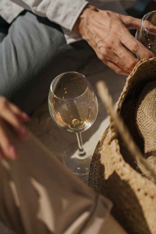 Free Close-up of a wine glass and wicker hat at an elegant outdoor picnic, capturing a relaxed summer vibe. Stock Photo