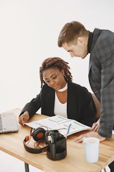 Two professionals discussing documents in a bright, modern office environment.