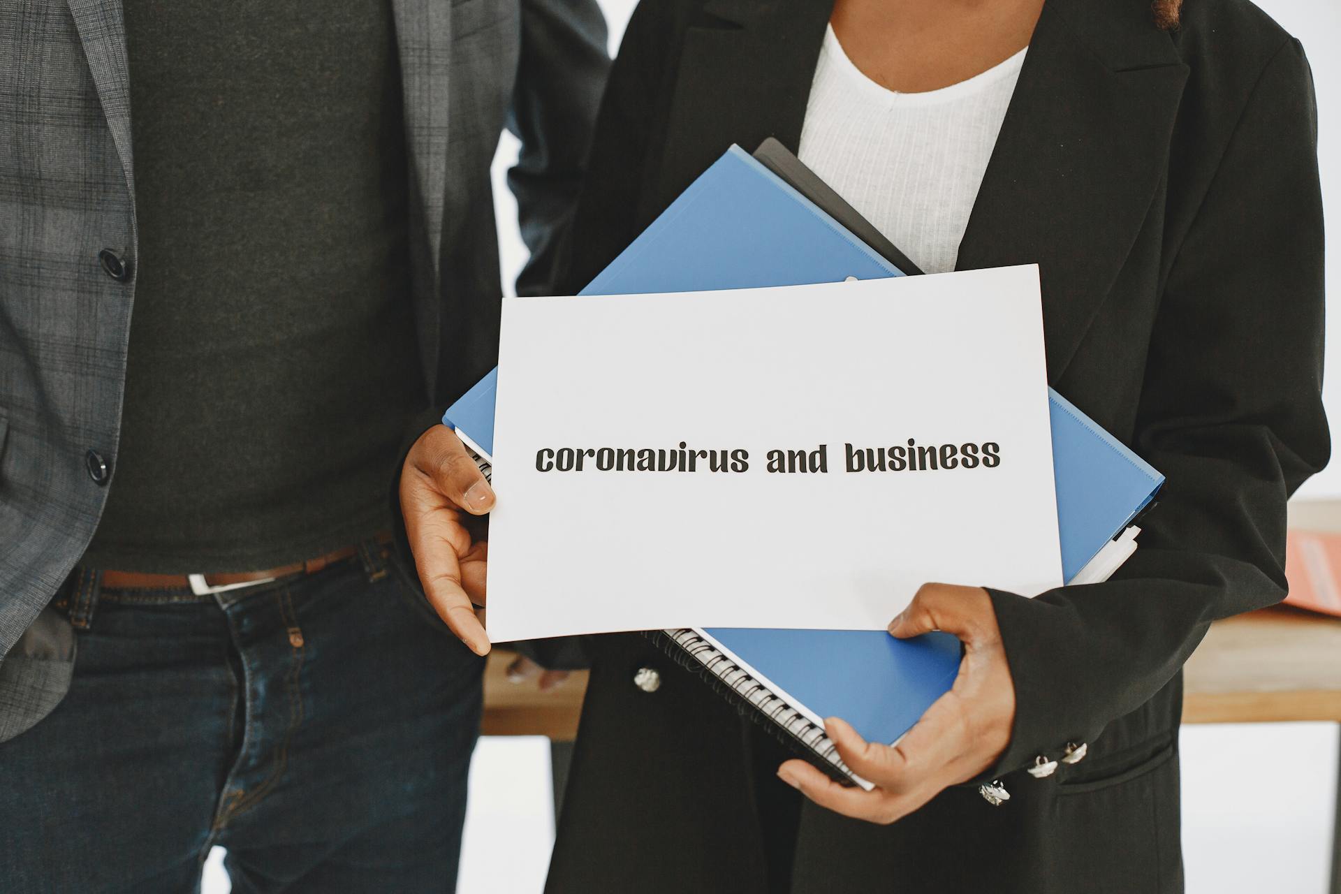 Business professionals hold a document about coronavirus impact with formal attire visible.