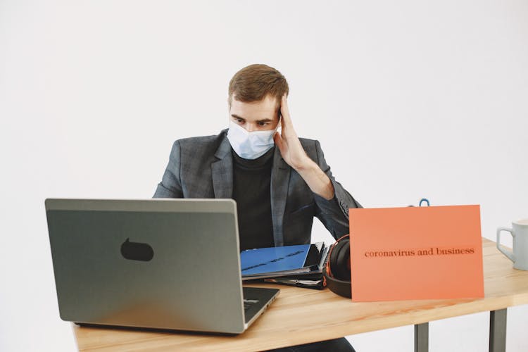 Frustrated Man In Face Mask Working On Laptop