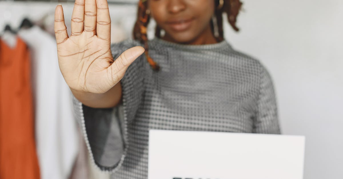 Photo by Gustavo Fring Woman holding a scam alert sign with a stop gesture indoors.
