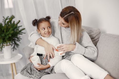 Free A mother and daughter enjoy cozy time together with hot drinks on a sofa. Stock Photo