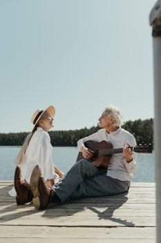 一对老夫妇在湖边享受了一个浪漫的吉他音乐下午