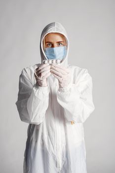 一名医护人员穿着防护服、戴着口罩，药丸装在防护服里，象征着安全和预防措施