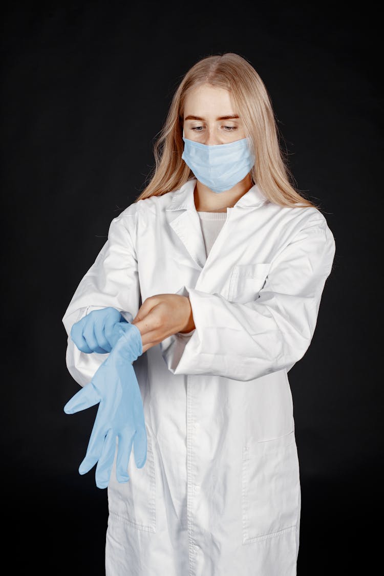 Healthcare Worker In A Mask Putting On Gloves