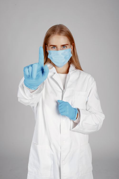 Free Healthcare worker in protective gear pointing upwards, emphasizing hygiene. Stock Photo