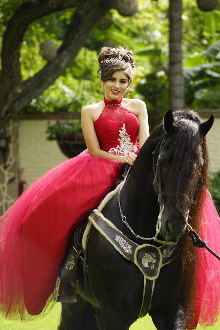 A Woman In Red Gown Riding A Black Horse