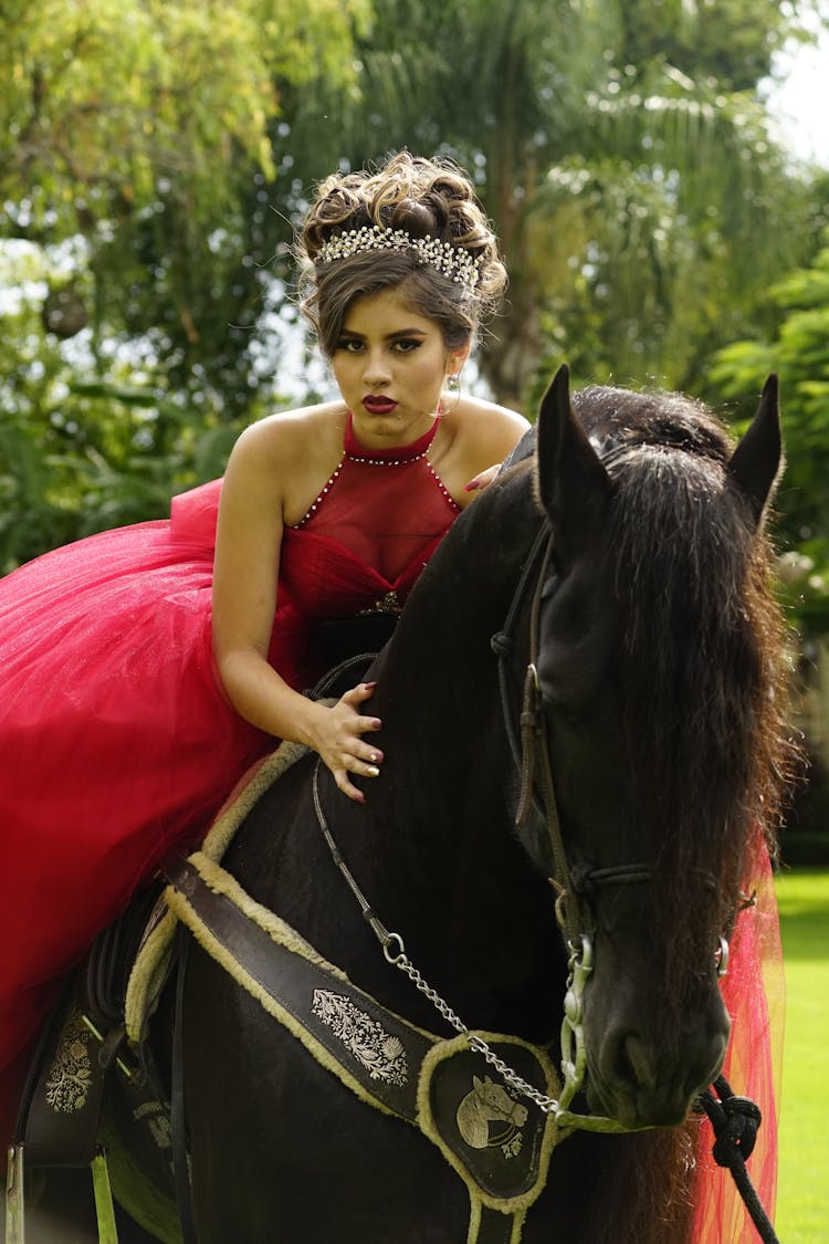 A Woman In Red Gown Riding A Black Horse