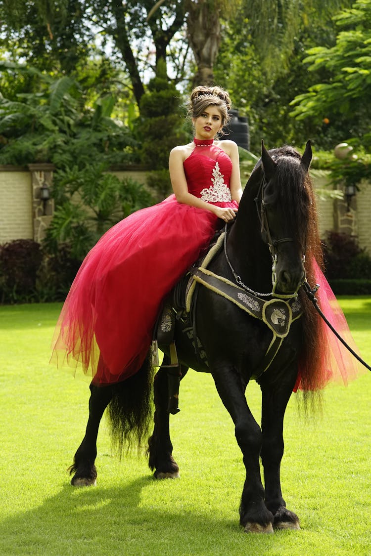 A Woman In Red Dress Riding A Black Horse