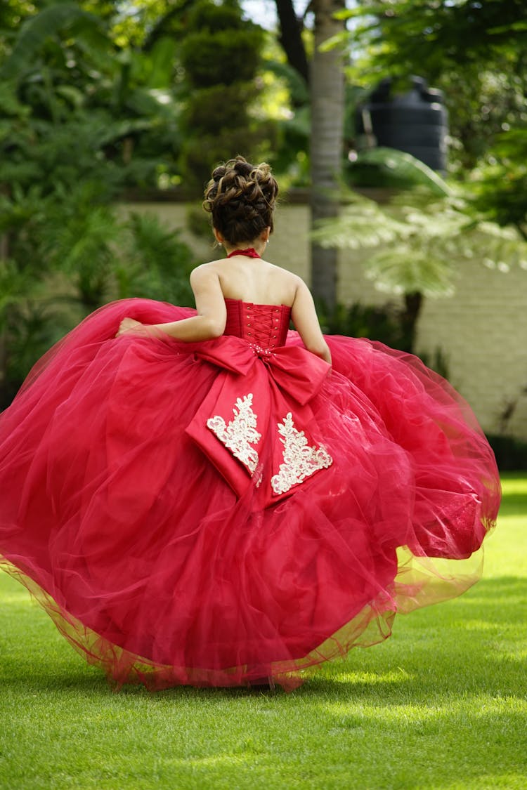 A Woman In Red Dress Running On A Grassy Field