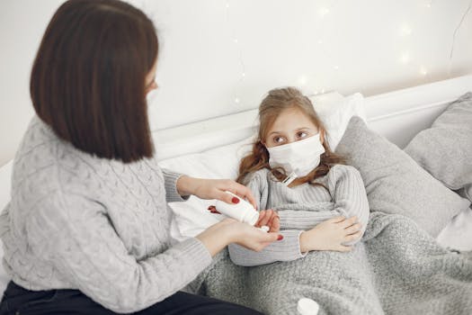 A mother helps her sick daughter wearing a face mask in bed, offering medicine.