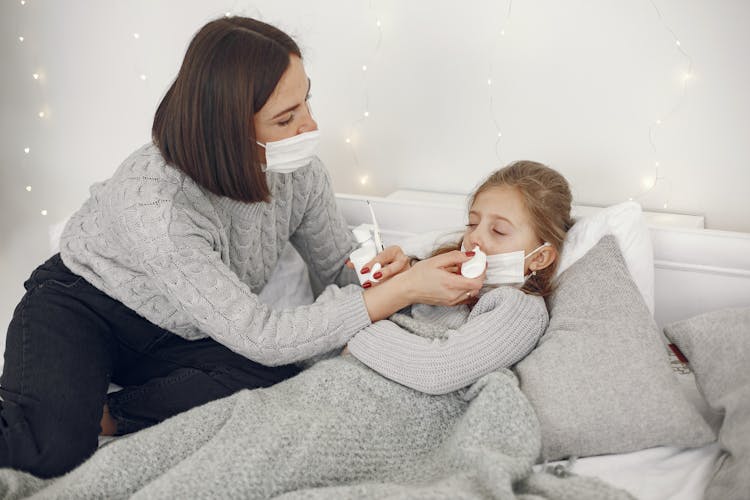 Mother Applying Nose Drops To A Sick Daughter 