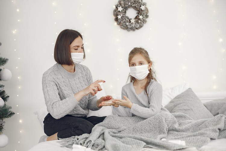 Mother And Child In Face Masks Sanitizing Hands