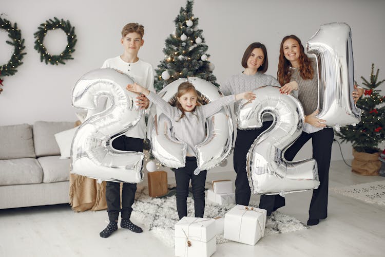 A Group Of People Holding 2021 Inflatables In A Living Room With Christmas Decors