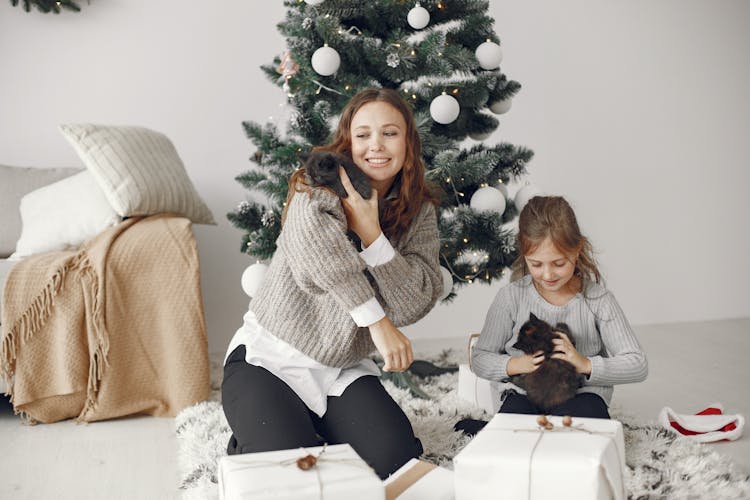 Mother And Daughter Playing With Kittens By Christmas Tree