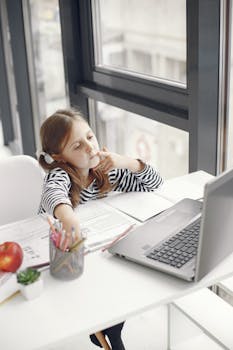 A young girl engaging in online learning at home using a laptop, emphasizing modern education.
