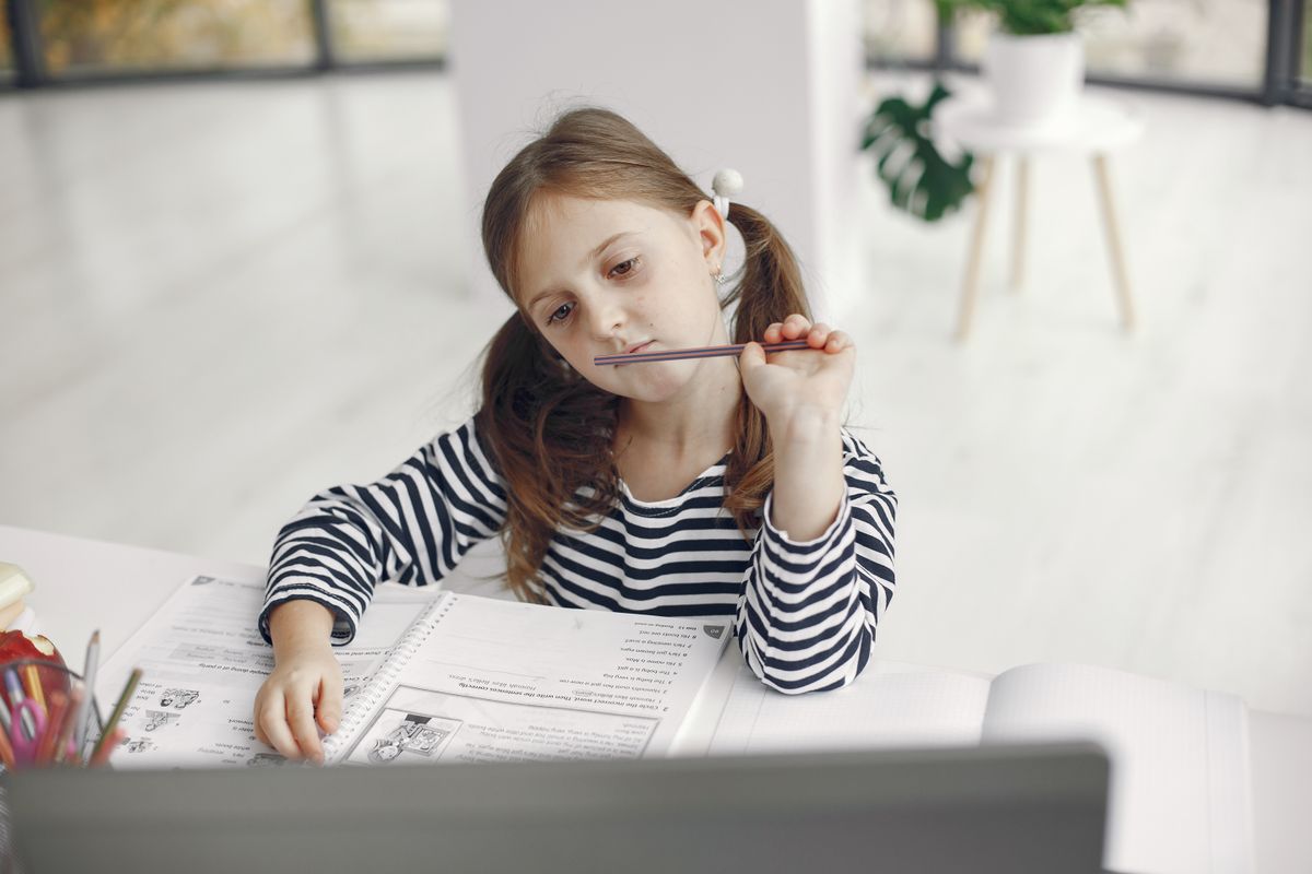 Young girl doing homework at a desk in a bright room