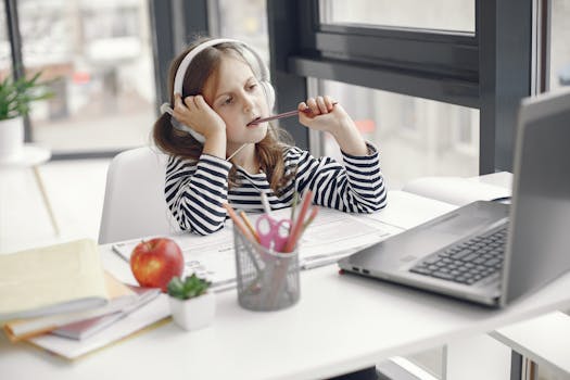 A child wearing headphones doing homework on a laptop indoors. Remote learning setup.