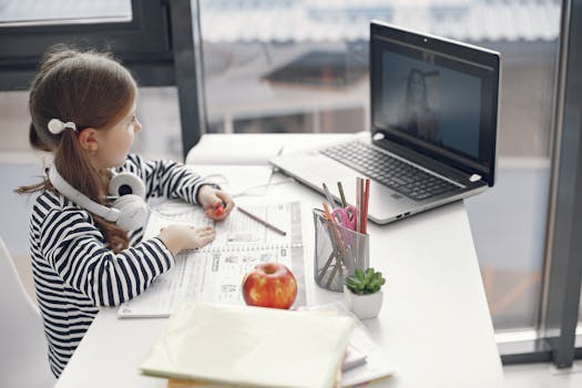 Girl studying online at home on a laptop with educational materials.