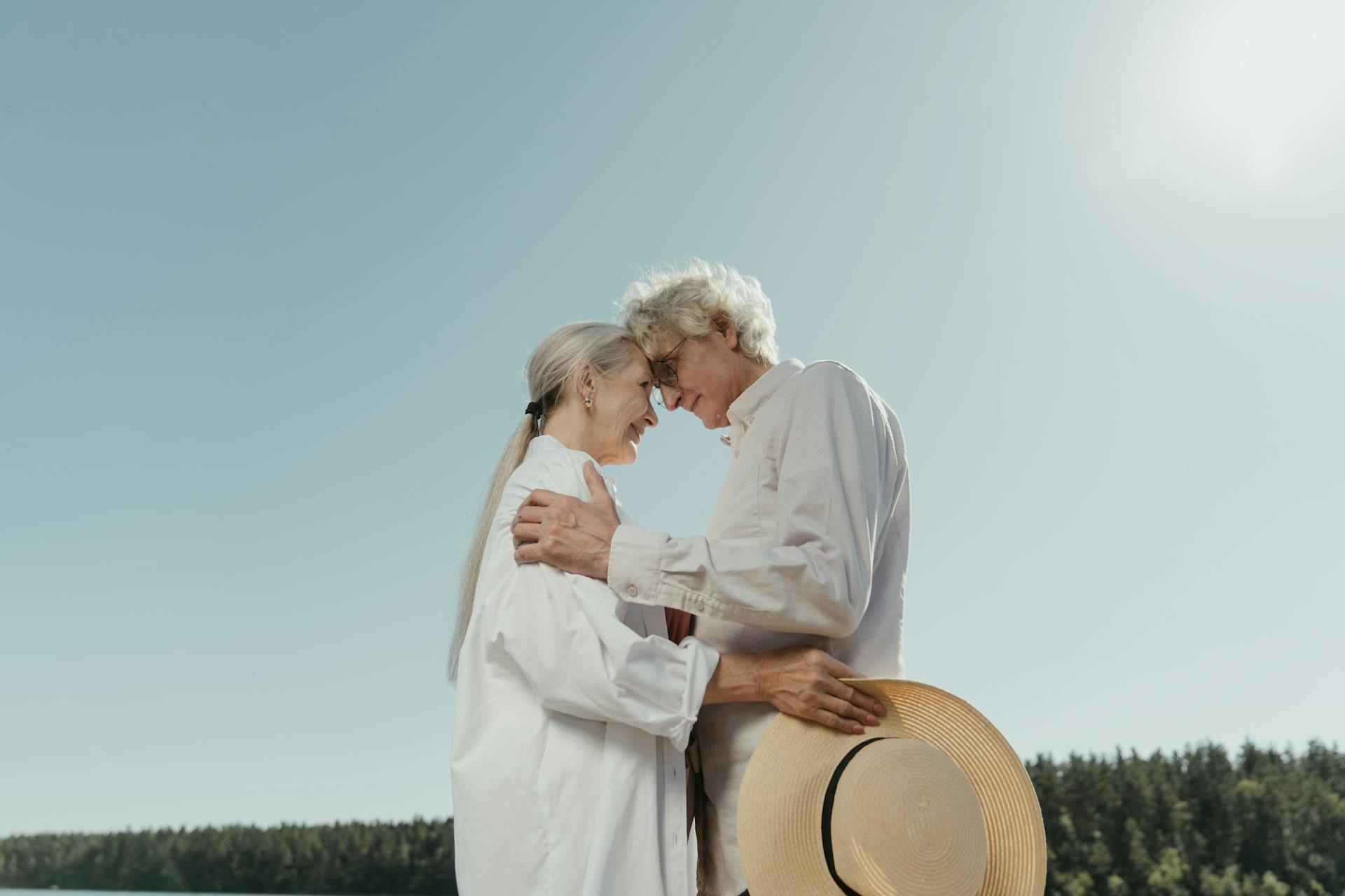 A senior couple shares a heartfelt embrace outdoors, symbolizing enduring love and connection.