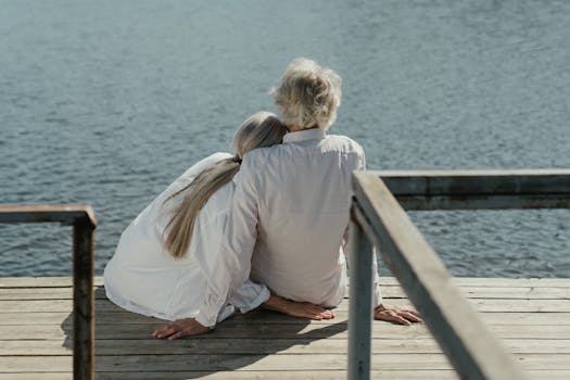 一对老年夫妇坐在湖边的木码头上，共享宁静时光，象征着他们持久的爱情