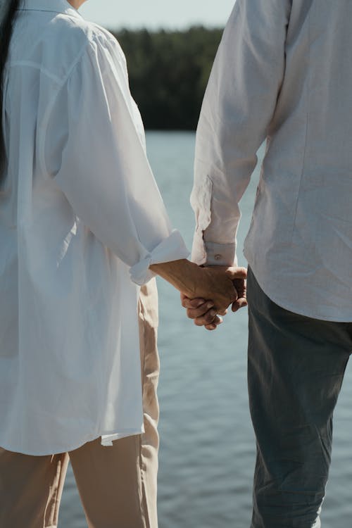 Homme En Chemise De Ville Blanche Et Pantalon Noir Se Tenant La Main Avec Une Femme à Manches Longues Blanc